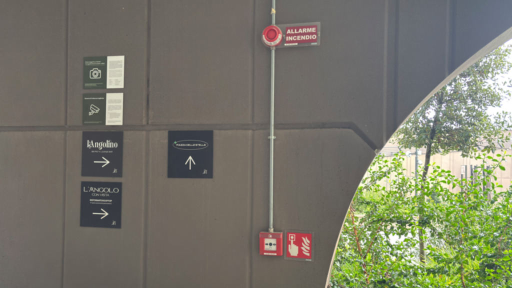 Segnaletica di sicurezza rossa con pittogrammi aggiornati secondo UNI EN ISO 3864-1 e 3864-3, con simboli di mano, fiamme e pulsante di allarme e scritta ‘Allarme antincendio’, installata in un cantiere CED INGEGNERIA