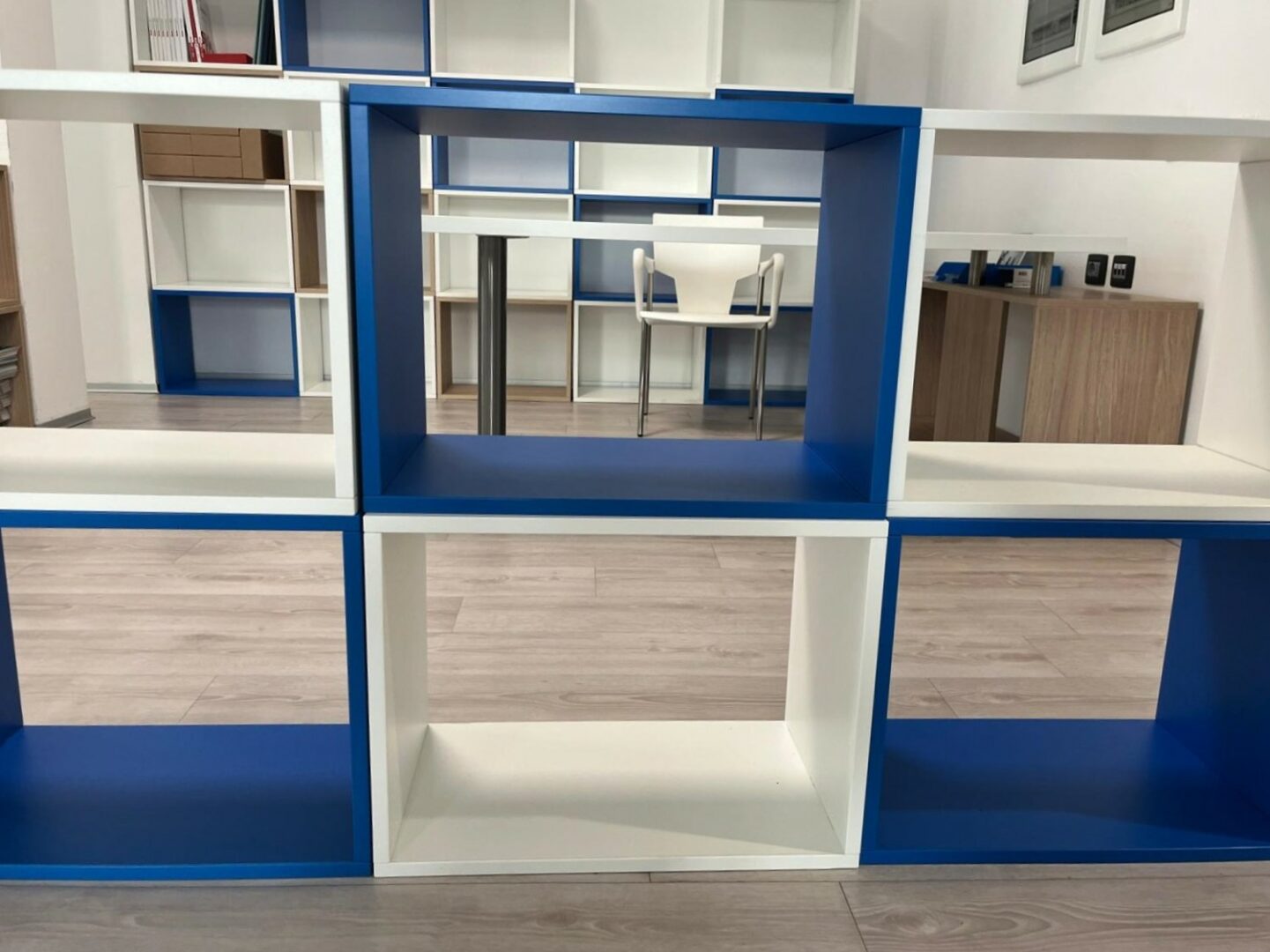 scaffalatura vuota blu e bianca con dietro una scrivania e una sedia